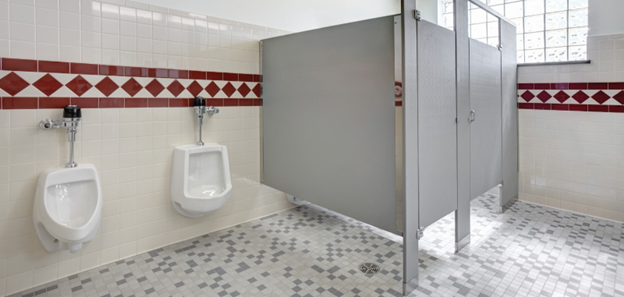 Image of a bathroom. The image features two urinals on the left hand side of the bathroom. To the right of the urinals, are two bathroom stalls. Running around the bathroom is a red tile pattern.