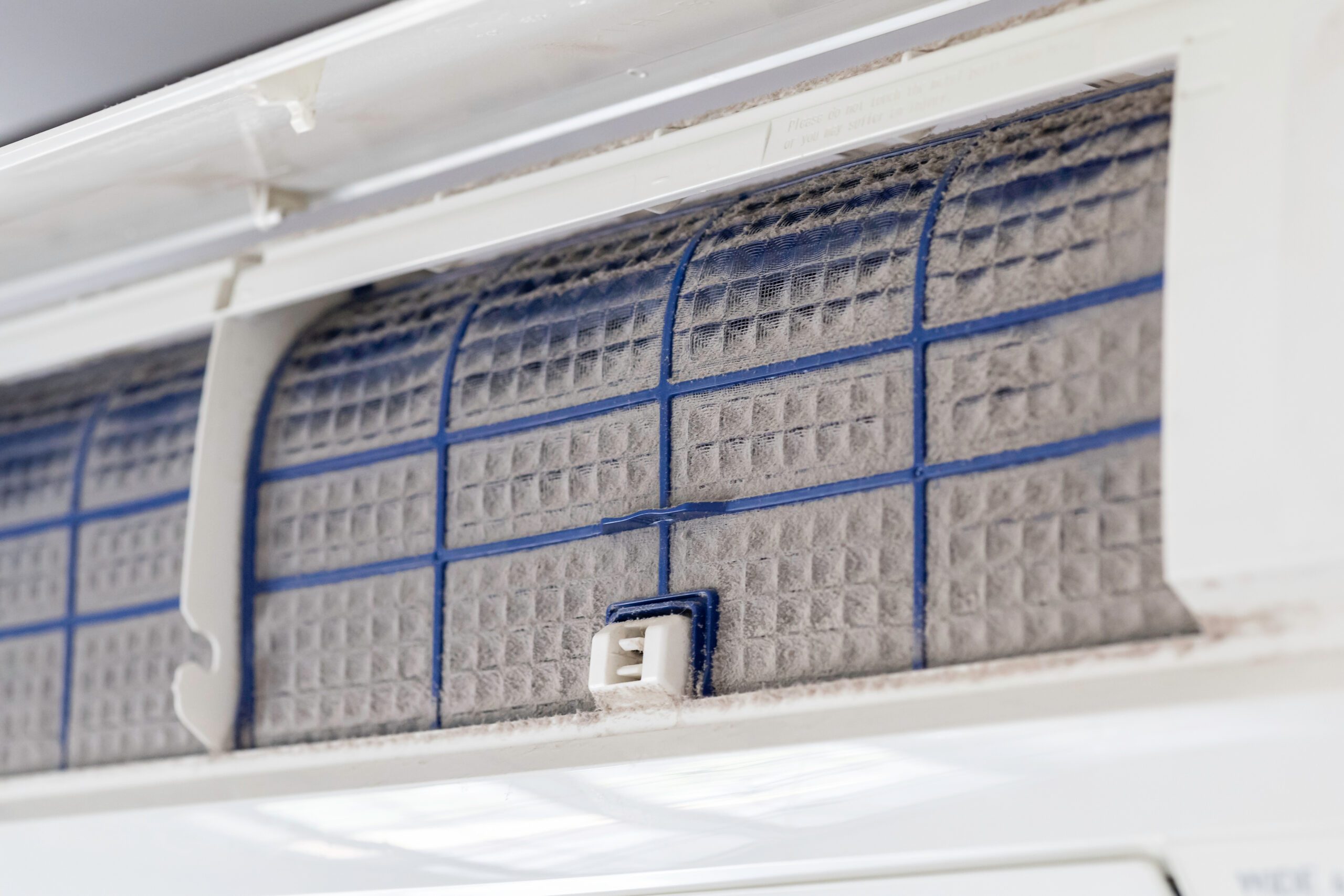 Clogged air conditioner filter covered in dust and debris requiring maintenance or replacement