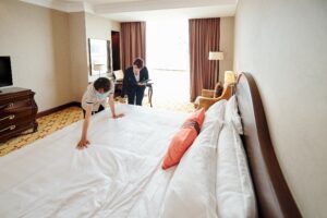 Family in hotel room with child playing while parents stand by window discussing accommodations