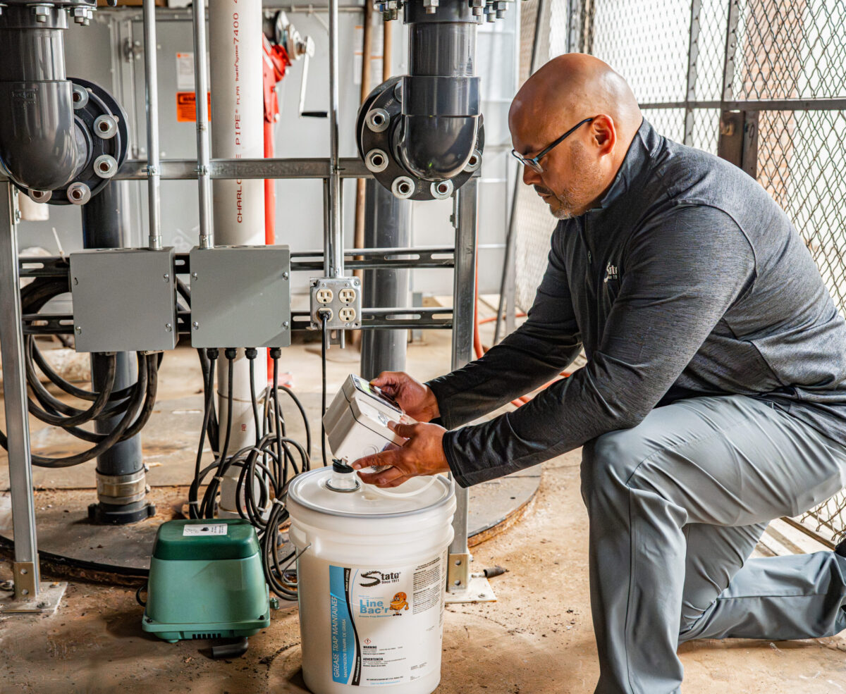 Technician servicing commercial drain pump and Line Bac'r system in facility mechanical room