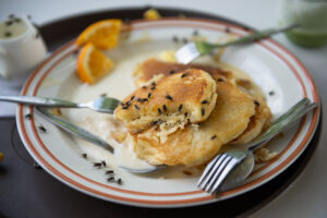 Flies swarming a plate of pancakes.