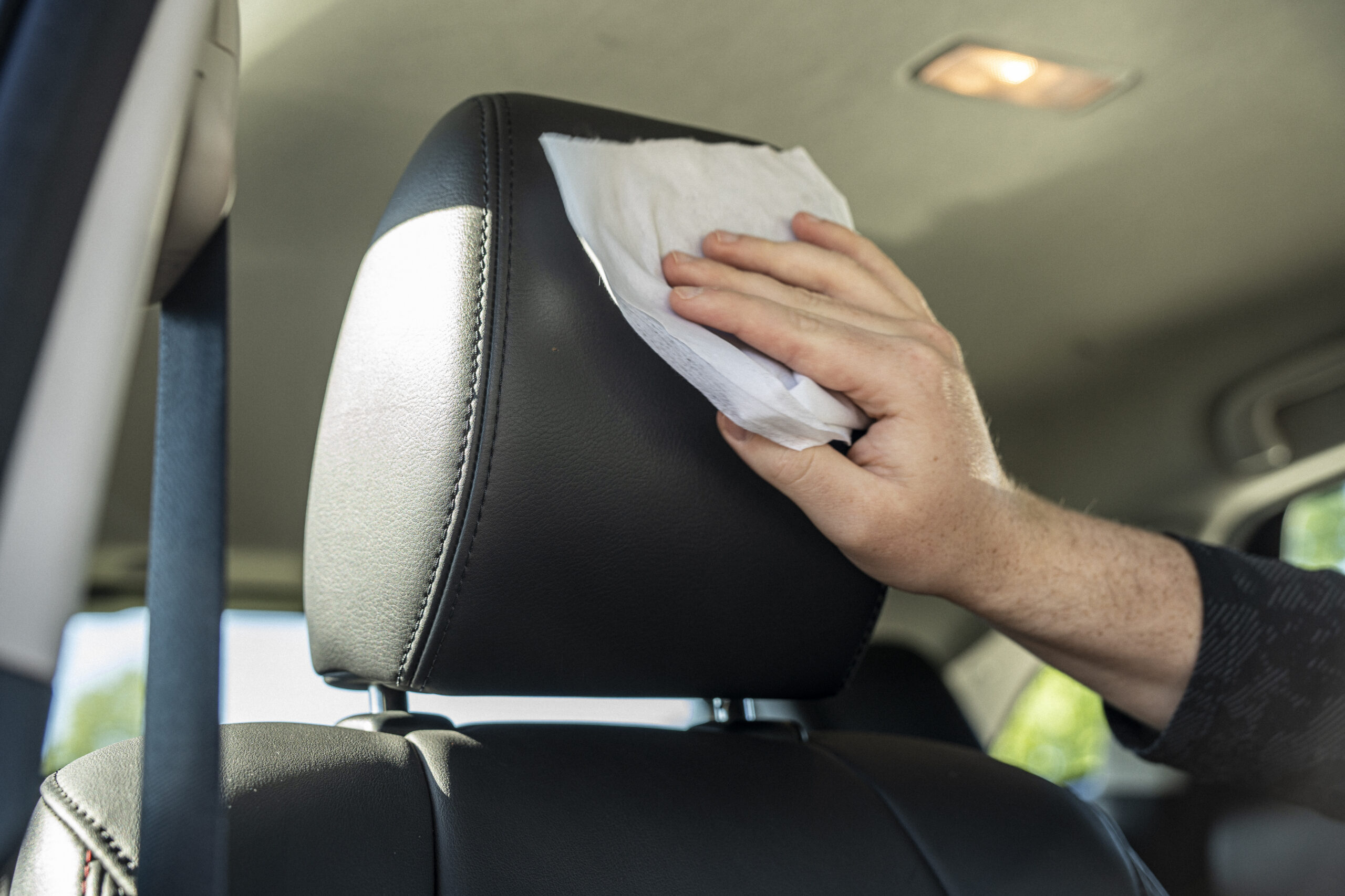 Man using Dream Gleam Protectant Wipes on car's leather headrest.